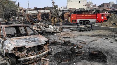 A photo taken on February 26, 2020 shows firefighters standing near a fire rescue vehicle as they douse burnt-out tyre market following deadly clashes in New Delhi. (AFP/File)