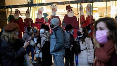 Pedestrians wear masks to prevent the spread of the Covid-19 as they walk past a store decorated as part of Christmas lightings in Paris, on Monday, December 6, 2021.&nbsp; (AP)