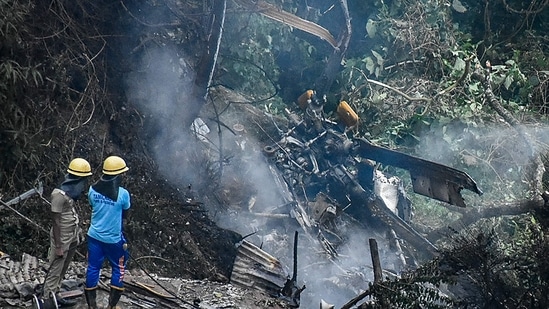 Firemen and rescue workers stand next to the debris of an IAF Mi-17V5 helicopter crash site in Coonoor, Tamil Nadu. (AFP)