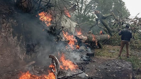 A man stands next to the burning debris of an IAF Mi-17V5 helicopter crash site in Coonoor, Tamil Nadu, on Wednesday.&nbsp;(AFP)
