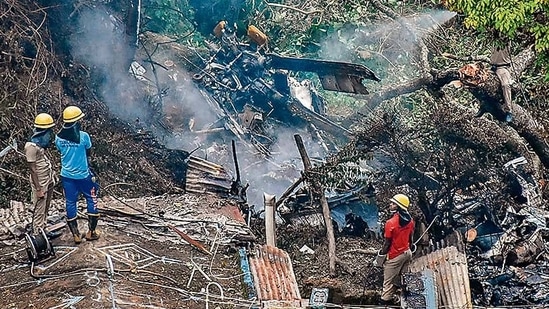 Firemen and rescue workers stand next to the debris of an IAF Mi-17V5 helicopter crash site in Coonoor, Tamil Nadu, on December 8, 2021 (AFP)