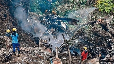 Firemen and rescue workers stand next to the debris of an IAF Mi-17V5 helicopter crash site in Coonoor, (AFP File Photo) Firemen and rescue workers stand next to the debris of an IAF Mi-17V5 helicopter crash site in Coonoor, (AFP File Photo)