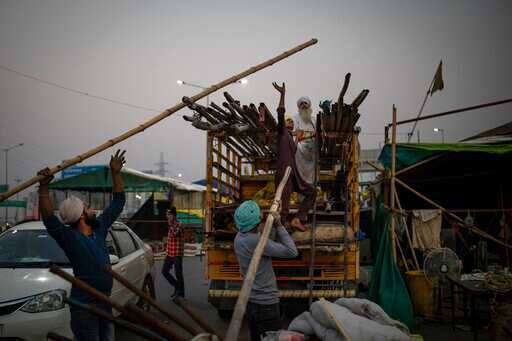 Farmers load bamboo and iron rods onto a truck as they dismantle temporary structures used during protests in Ghazipur and prepare to return home. (AP) Farmers load bamboo and iron rods onto a truck as they dismantle temporary structures used during protests in Ghazipur and prepare to return home. (AP)