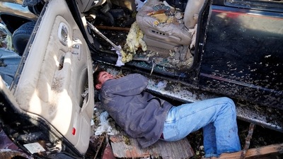 A man makes an adjustment under his truck before attempting to drive it out of a pile of debris. (REUTERS)