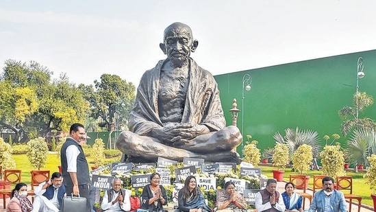 Suspended Rajya Sabha MPs stage a protest near the statue of Mahatma Gandhi demanding revocation of their suspension, during the Winter Session of Parliament, in New Delhi on Monday. (PTI)