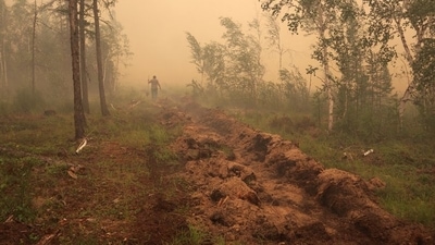 A man digs a control line during the work on extinguishing a forest fire near the village of Magaras in the region of Yakutia, Russia July 17, 2021.&nbsp; (REUTERS)