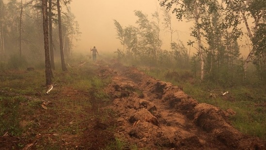 A man digs a control line during the work on extinguishing a forest fire near the village of Magaras in the region of Yakutia, Russia July 17, 2021.&nbsp;(REUTERS)