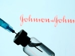 A vial and syringe are seen in front of a displayed Johnson&amp;Johnson logo in this illustration.&nbsp;