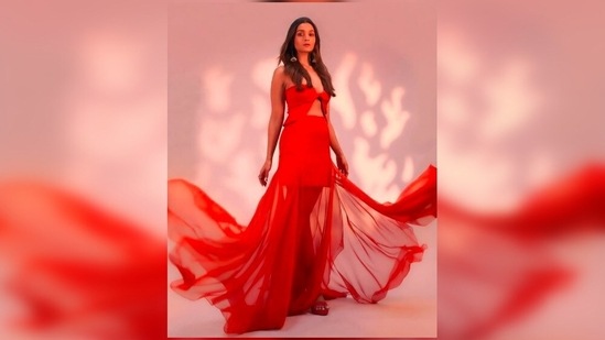 Alia Bhatt painted the town red as she stepped out to attend the motion poster launch event of Brahmastra in a red cut-out strapless top and a mini skirt attached with a long netted wrap-around material.(Instagram/@vandafashionagency)