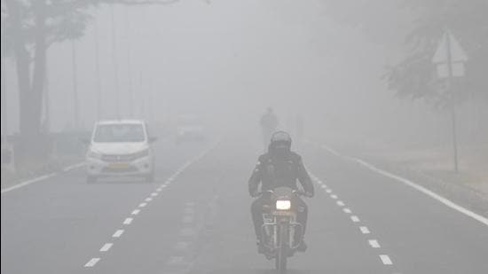 Commuters make way through thick fog on the Sector 42-43 dividing road in Chandigarh on Friday. Similar weather conditions will continue in the coming days. (Keshav Singh/HT)