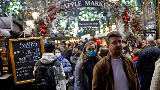 Shoppers, some wearing face coverings to combat the spread of Covid-19, walk past stalls and shops in the Apple Market in Covent Garden on the last Saturday for shopping before Christmas, in central London on December 18, 2021.&nbsp;(AFP)