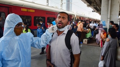 A healthcare worker of BrihanMumbai Municipal Corporation collects swab samples of an outstation passenger for Covid-19 test, at Dadar railway station in Mumbai, on Sunday. (PTI Photo) A healthcare worker of BrihanMumbai Municipal Corporation collects swab samples of an outstation passenger for Covid-19 test, at Dadar railway station in Mumbai, on Sunday. (PTI Photo)