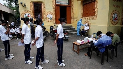 A healthcare worker wearing personal protective equipment (PPE) takes a swab from a police officer for a rapid antigen test as others line up at a special testing center for Gujarat Police, amid the coronavirus disease (COVID-19) outbreak, in Ahmedabad, India (REUTERS)