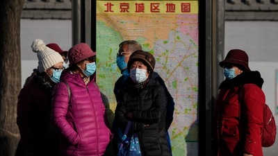 Commuters wearing face masks to protect against the coronavirus wait for their buses at a bus stand in Beijing on Sunday. (AP Photo) Commuters wearing face masks to protect against the coronavirus wait for their buses at a bus stand in Beijing on Sunday. (AP Photo)