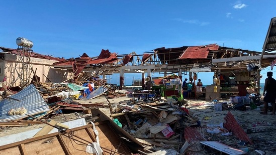 Residents stand next to a destroyed market building in General Luna town, Siargao island, Surigao del norte province, a day after super Typhoon Rai devastated the island.&nbsp;(AFP)