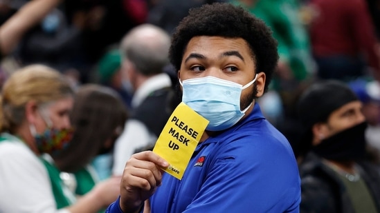 An usher holds a sign reminding people to wear a mask during an NBA basketball game on Saturday.(AP File Photo)