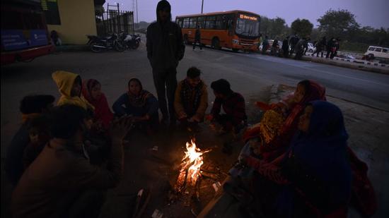 People warm themselves around a bonfire on a cold winter evening at Sarai Kalen Khan, in New Delhi. (Sanjeev Verma/HT PHOTO)