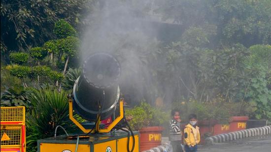 Children walk past a mist machine spraying water to curb air pollution amid smoggy conditions in New Delhi. (AFP)