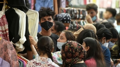 People wearing masks in improper way, shop at a market at Bandra in Mumbai, on Friday. (PTI Photo)