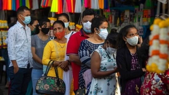 People wearing face masks wait for their turn to enter a church to offer prayers on Christmas in Mumbai.(AP)