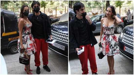 Malaika's dress also comes with a bow-adorned black belt cinched on the waist. The star accessorised the ensemble with pointed bright red pumps, a black face mask to stay safe, and a black patterned leather top handle bag.(HT Photo/Varinder Chawla)