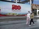 Pedestrians pass a billboard celebrating the 100th anniversary of the founding of the Communist Party of China in Wuhan, Hubei Province, China, on Thursday, Dec. 23, 2021. China set a weaker-than-forecast yuan fixing for a record 15th day on Friday as it seeks to curb currency gains that threaten to undermine its economic recovery.&nbsp;