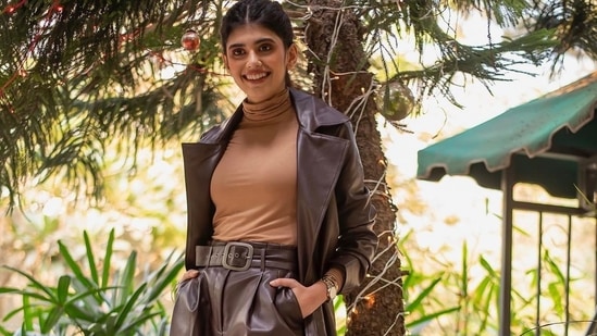 Taking to her social media handle, Sanjana shared a slew of pictures featuring her donning a caramel brown turtleneck, tucked inside a pair of dark brown leather pants that were held at the waist with a matching belt and layered with a dark brown leather trench coat.&nbsp;(Instagram/sanjanasanghi96)