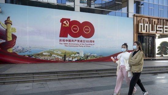 Pedestrians pass a billboard celebrating the 100th anniversary of the founding of the Communist Party of China in Wuhan, Hubei Province, China, on Thursday, Dec. 23, 2021. China set a weaker-than-forecast yuan fixing for a record 15th day on Friday as it seeks to curb currency gains that threaten to undermine its economic recovery. (Bloomberg)