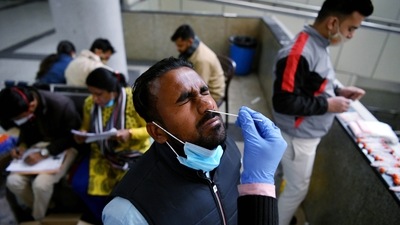 A healthcare worker takes a nasal swab sample of a passenger for the Covid-19 test, at Kashmere Gate ISBT, in view of rising Omicron cases, in New Delhi on Monday.&nbsp; (ANI Photo)