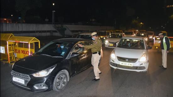 Delhi police personnel check vehicles during night curfew, at Connaught Place in New Delhi on Monday. (ANI)