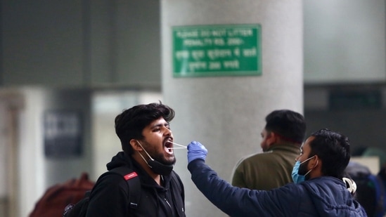 A healthcare worker collects a swab sample of a passenger at Kashmere Gate ISBT amid a surge in Omicron cases, in Delhi on Tuesday. (ANI)