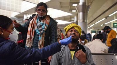 A healthcare worker takes a nasal swab sample of a passenger for the Covid-19 test at Kashmere Gate ISBT. (ANI)
