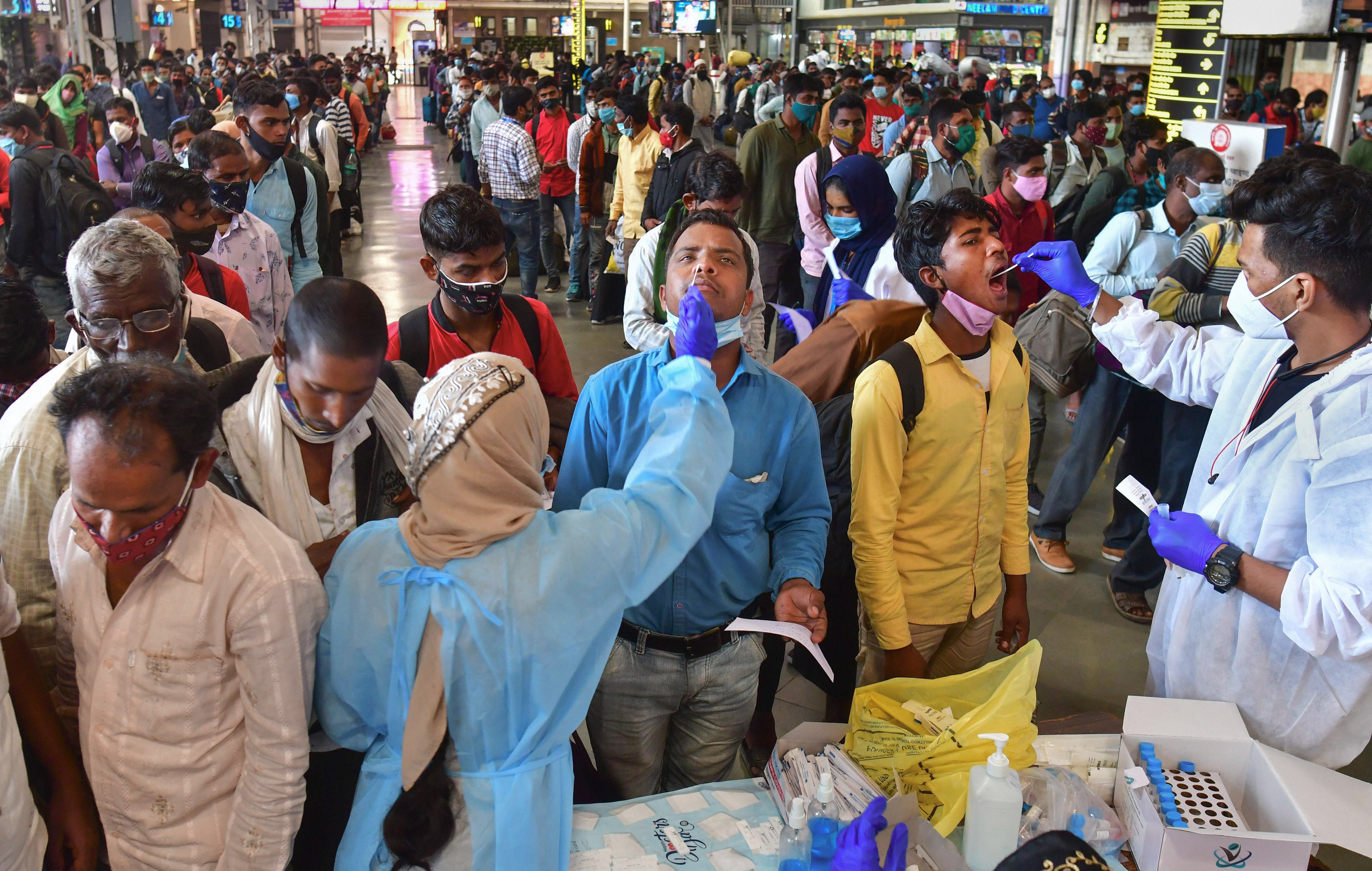 A health worker collects swab samples of an outstation passenger for Covid-19 at CSMT railway station in Mumbai on Wednesday. (PTI) A health worker collects swab samples of an outstation passenger for Covid-19 at CSMT railway station in Mumbai on Wednesday. (PTI)
