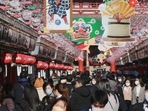 People wearing face masks to protect against the spread of the coronavirus walk under decorations for new year in Tokyo. (AP)