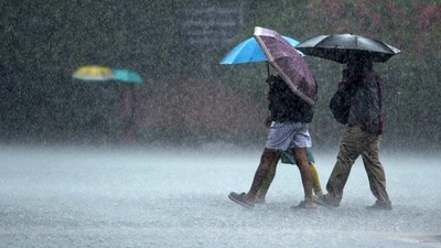 Commuters make their way through a street during a heavy rain shower in Chennai on December 30, 2021. (AFP)