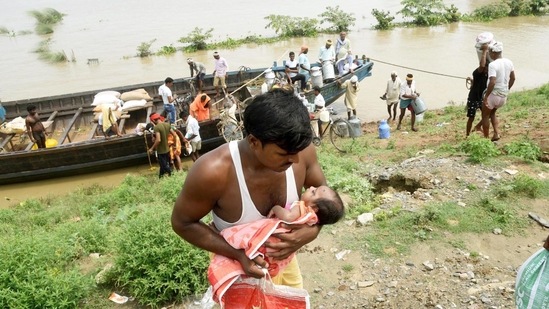 A flood victim carries a child after disembarking from a boat while heading to higher grounds for shelter, at Digha Ghat, in Patna, on August 17. According to preliminary estimates in early September, 53 people died and 2 million people, spread across 1652 villages in 83 blocks of 16 districts, were affected by this year’s floods while 219,000 residents were evacuated.(Santosh Kumar / HT Photo)