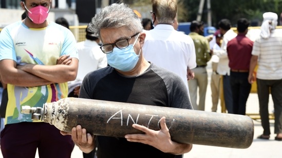 A man carries an oxygen cylinder marked with a Covid-19 positive patient's name, at Mayapuri industrial area, in New Delhi, on May 8. The Capital, like several other cities across the country, grappled with a severe shortage of medical oxygen and health care infrastructure was overrun among a seismic rise in Covid-19 infections, fuelled by the Delta variant of the coronavirus.(Arvind Yadav / HT Photo)