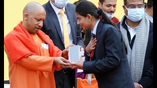 Chief minister Yogi Adityanath hands over a mobile phone to a student at a distribution programme of tablets and smartphones to one crore youth on the 97th birth anniversary of former Prime Minister Atal Bihari Vajpayee, at Ekana Sports City, in Lucknow recently. (ANI Photo)
