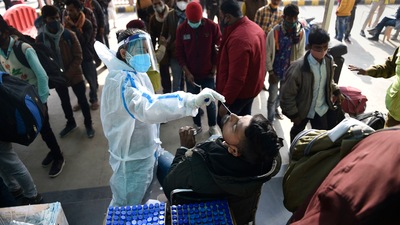 A health worker collects swab samples of passengers to conduct a Covid-19 test at the Anand Vihar railway station near New Delhi. (PTI)