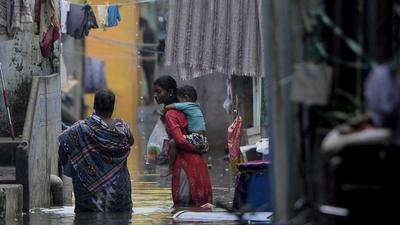 A woman carrying her infant wades along a waterlogged residential area after heavy rainfall in Chennai on December 31. (AFP) A woman carrying her infant wades along a waterlogged residential area after heavy rainfall in Chennai on December 31. (AFP)