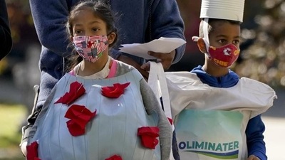 Dressed as coronavirus and hand sanitizer for Halloween, Daphne Origanti, age 9, and her brother Owen, age 7, walk between houses as they trick-or-treat Saturday, October 31, 2020, in Overland Park, Kan. (AP Photo/Charlie Riedel) Dressed as coronavirus and hand sanitizer for Halloween, Daphne Origanti, age 9, and her brother Owen, age 7, walk between houses as they trick-or-treat Saturday, October 31, 2020, in Overland Park, Kan. (AP Photo/Charlie Riedel)