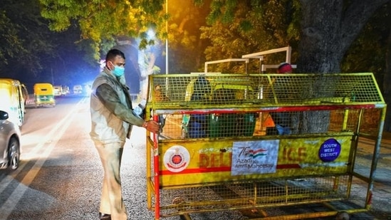 A Delhi Police personnel puts in place barricades at the entrance of Hauz Khas village in New Delhi on New Year’s eve on Friday. (Amal K S/HT photo)