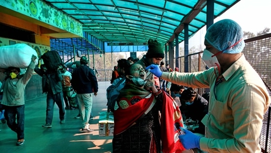 A healthcare worker collects a swab sample of a passenger for the Covid-19 testing at New Delhi Railway Station. 