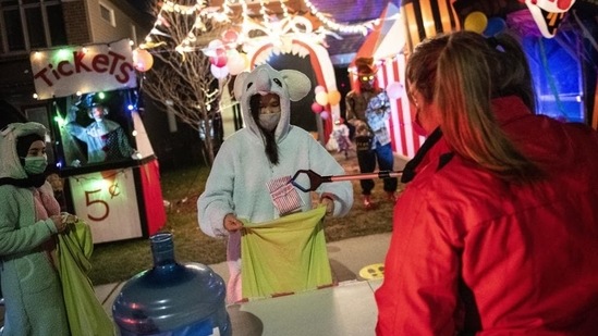 A resident gives out Halloween treats using a reacher-grabber tool as a measure against Covid-19, as part of a fundraiser for the food bank at a decorated home in Ottawa Ontario, Saturday, October 31, 2020. (AP Photo/Justin Tang)