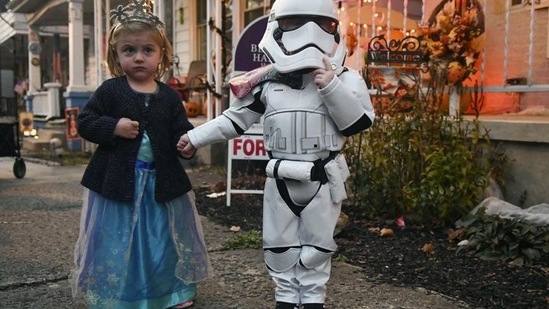 Julianna Seltzer, 2, left, and Chase Lessig, 3, both of Reading, Pa., hold hands while trick-or-treating on Paxson Avenue in Schuylkill Haven, Pa., on Saturday evening, October 31, 2020. (AP Photo/Jacqueline Dormer)