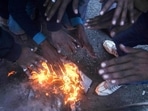 People warm themselves next to a fire during a cold winter morning. People warm themselves next to a fire during a cold winter morning. 