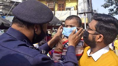 A policeman puts a mask on a child during a Covid awareness campaign and masks distribution by Kolkata Police in view of rising cases, at New Market, in Kolkata on Sunday. (ANI) A policeman puts a mask on a child during a Covid awareness campaign and masks distribution by Kolkata Police in view of rising cases, at New Market, in Kolkata on Sunday. (ANI)