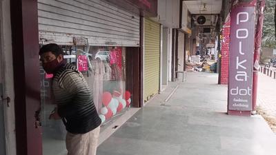 A shopkeeper downing the shutter in Panchkula in view of Haryana government’s order to close markets by 5pm. (Sant Arora/HT)