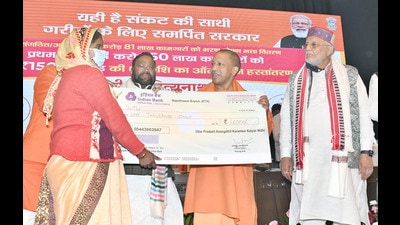 Chief minister Yogi Adityanath handing over a symbolic cheque of  ₹1000 to a migrant labourer in Lucknow on Monday. (HT)