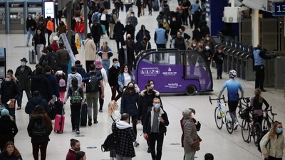 People wearing protective face masks walk through Waterloo train station, amid the Covid-19 outbreak, in London, Britain. (Reuters)